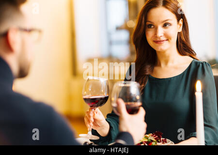 Felice giovane donna tintinnio wineglass con uno di suo marito in ristorante Foto Stock