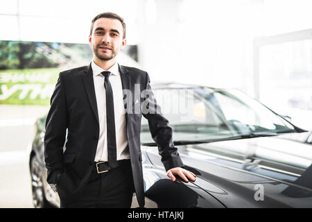 Venditore professionale a sorridere di fronte a una nuova auto presso la concessionaria professione lavoro occupazione proprietarie di acquistare al dettaglio lo stile di vita di lusso concept Foto Stock