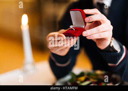 Maschio con le mani di velluto rosso scatola contenente anello di fidanzamento con brillante Foto Stock