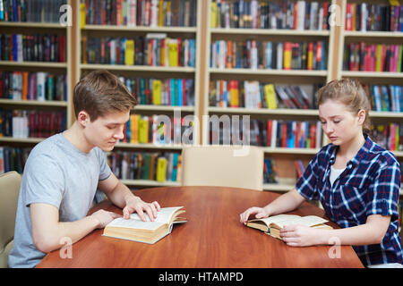 Due seri studenti concentrando sulla lettura in biblioteca Foto Stock