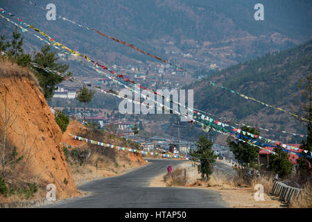 Il Bhutan, Thimphu. Tipica vista stradale con la preghiera le bandiere e la città di Thimphu in distanza. Foto Stock