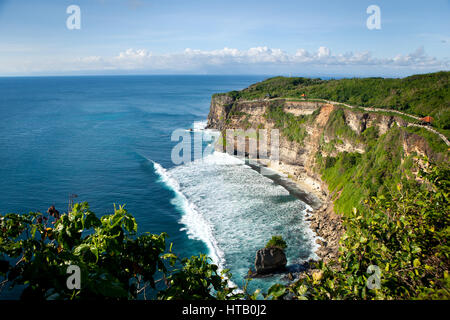 Vista panoramica dell'oceano con onde con un alta rupe in una giornata di sole con nuvole. Uluwatu, Bali Foto Stock