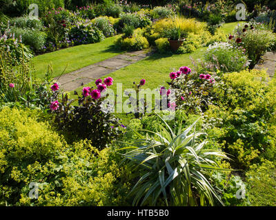 Chenies Manor sunken garden, Buckinghamshire. Sole serale enhanced i colori del fogliame, Lady del mantello e rosa scuro dalie aggiunta alla loro bellezza. Foto Stock