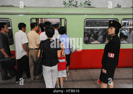 09.08.2012, Pyongyang, Corea del Nord - Una piattaforma supervisore sorge accanto alla metropolitana di attesa in corrispondenza di una stazione di Pyongyang. Foto Stock