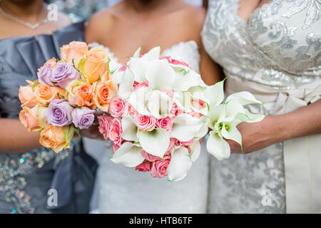 Due damigelle e una sposa tenendo due mazzi di fiori Foto Stock