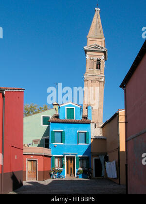 Case dai colori vivaci e un alto campanile si innalzano contro il cielo azzurro di Burano, Venezia. Italia Foto Stock