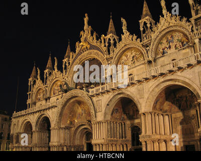 Vista notturna della Basilica di San Marco a Venezia con dettagli architettonici intricati e grandi sculture. Venezia. Italia Foto Stock