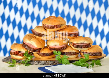 Forno tradizionale fresca bavarese pagnotta di carne su croccanti panini, la bandiera bavarese in background Foto Stock