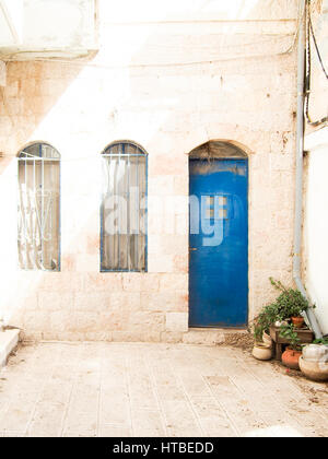 Una luminosa porta blu si staglia contro un bianco edificio di pietra a Gerusalemme, Israele. Foto Stock