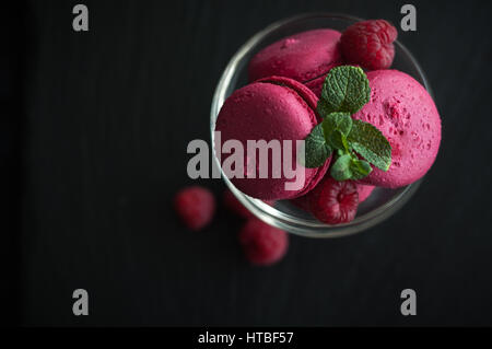 Amaretti rosa con lamponi in coppa su sfondo nero Foto Stock