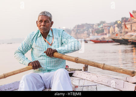 Un uomo indiano remare una barca per escursioni sul fiume Gange, Varanasi (India). Foto Stock