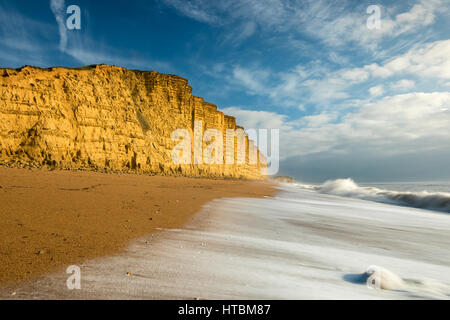 Onde che si infrangono sulla spiaggia al di sotto di East Cliff, West Bay, Jurassic Coast, Dorset, England, Regno Unito Foto Stock