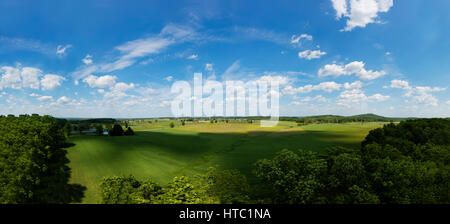 Cielo blu su un campo verde con macchie di luce del sole. Alberi circondano questo storico campo di battaglia di Gettysburg, PA Foto Stock