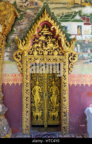 Foglia oro coperto sculture in legno in una porta di Wat Pa Phai tempio a Luang Prabang, Laos. Foto Stock