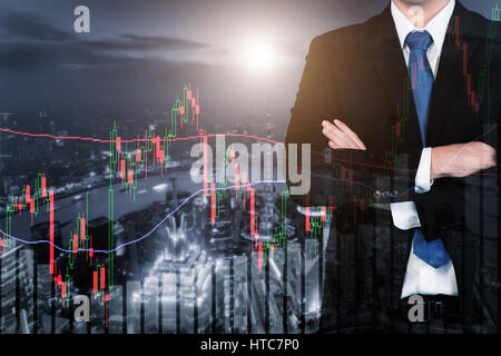 Doppia esposizione di imprenditore e di negoziazione del mercato azionario grafico e bar sulla città di notte. Affari finanziari e concetto di trading. Foto Stock