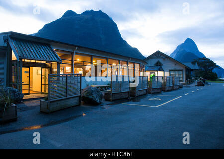 Milford Sound, Parco Nazionale di Fiordland, Southland, Nuova Zelanda. L Anatra Blu Café accesa al crepuscolo, Mitre Peak visibile in background. Foto Stock