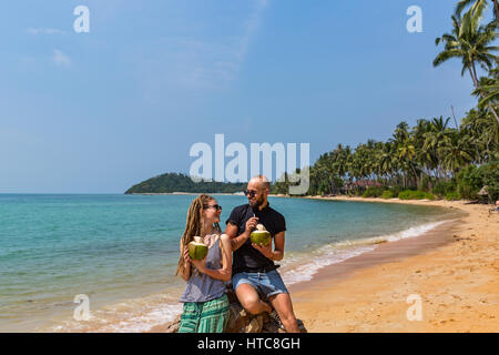 Coppia giovane bere freschi succo di cocco sulla spiaggia Foto Stock