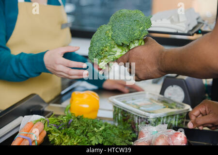 Il cliente consegna un assistente vendite broccoli Foto Stock