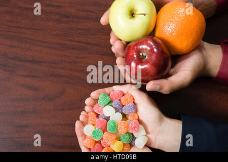 Caramelle e frutta essendo trattenuto Foto Stock