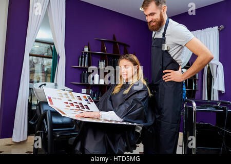 Donna client sceglie il colore della vernice con parrucchiere uomo in un salone di bellezza. Foto Stock