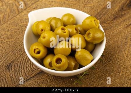 Olive farcite in heap la ciotola su uno sfondo di legno Foto Stock