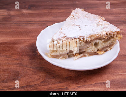 Un grande pezzo di torta cosparsa di zucchero a velo su una piastra bianca Foto Stock