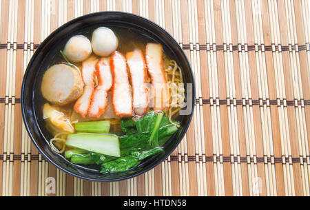 Uovo zuppa di noodle al rosso con carne di maiale arrosto su sfondo di legno.