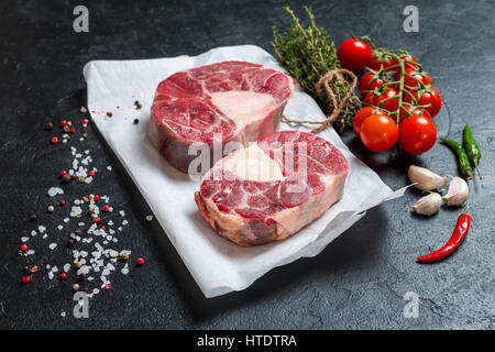 Materie Stinco di vitello fette di carne e gli ingredienti per Osso Buco cottura su sfondo nero, vista dall'alto Foto Stock