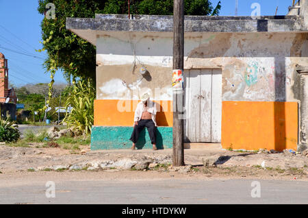 Uomo messicano nel cappello da cowboy si siede sulla strada fuori dell edificio colorato Foto Stock