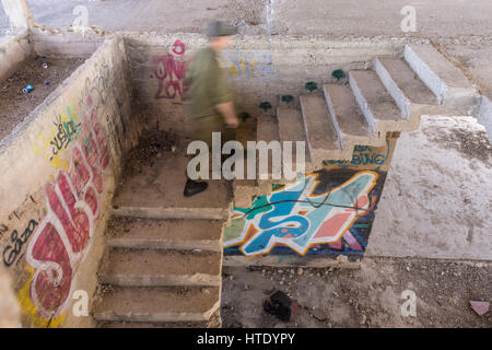 Tell-el-Ful. Gerusalemme, Israele. Un soldato israeliano si arrampica un graffiti-scala coperta a incompiuto, il palazzo estivo del Re Hussein di Giordania. Foto Stock