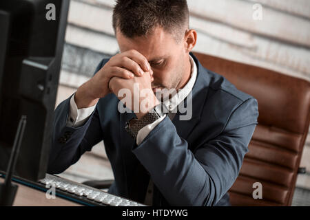 Stanco uomo d affari al lavoro in ufficio tenendo la testa sulle mani. Assonnato lavoratore nelle prime ore del mattino dopo la fine del lavoro notturno. Superlavoro, rendendo mis Foto Stock