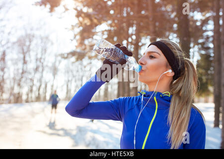 Ragazza beve l'acqua sull'allenamento invernale per esterno Foto Stock