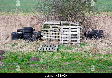 Una vista di vecchi pallet in legno e pneumatici in gomma da terreni agricoli sulla Norfolk Broads a Runham, Norfolk, Inghilterra, Regno Unito. Foto Stock