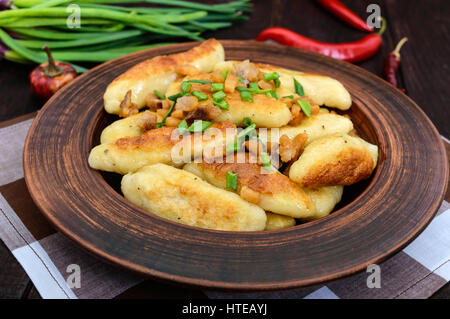 Popolare tradizionale, ceco, ungherese, piatto tedesco: patata knedli canederli con fette di pancetta fritta, piccante pepe rosso e i cipollotti. Foto Stock