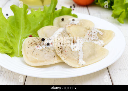 Ravioli italiano canederli in forma di cuore su una piastra bianca su sfondo di legno. Foto Stock