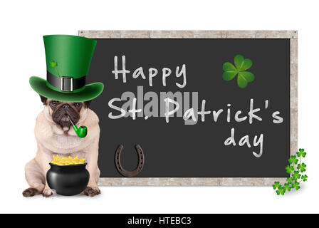 Carino pug cucciolo di cane con leprechaun hat per st. Patrick's day tubo di fumo, seduta accanto alla lavagna vuota firmare con il ferro di cavallo e shamrock, su bianco Foto Stock