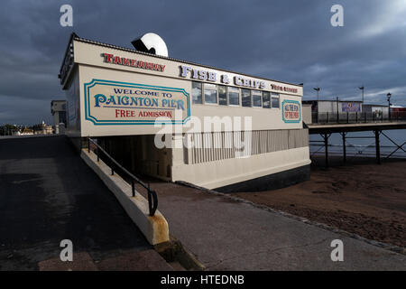 Detectorists metallo sul rilevamento di Paignton Beach con Frgate o nave da guerra ormeggiata in Torbay con Berr testa in background Foto Stock