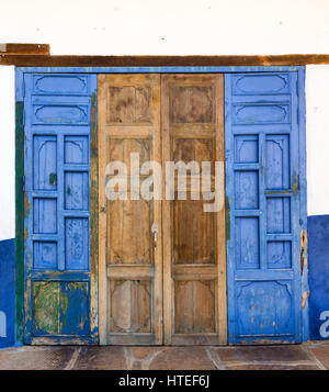 Un mosaico di blu e indossato le texture in legno su intricate tralicciati porte in Barichara, Colombia. Foto Stock