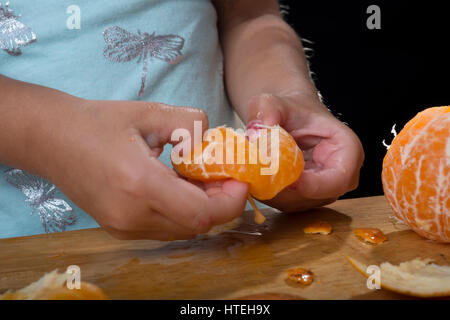 Peeling mani un arancio mandarino Foto Stock