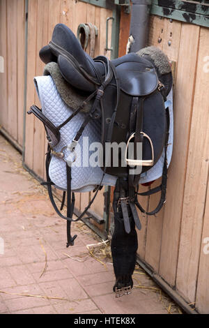 Sella in cuoio per sport equestri appeso nel fienile Foto Stock