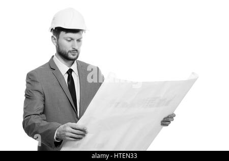 Architetto professionista. In bianco e nero girato di gravi barbuto architetto maschio in hardhat esaminando gli schemi architetturali isolato su bianco professare Foto Stock