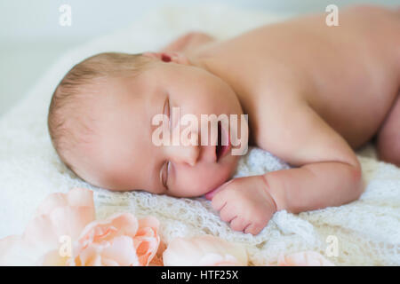 Sorridente neonato. Testa e spalle colpo di sonno due settimane vecchio neonato. Sfondo luminoso, dormendo ragazza neonata Foto Stock
