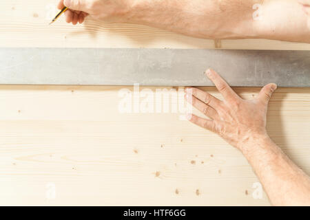 Le mani di un falegname di misura e wiriting giù sul pannello di legno con una matita; nozione di falegname artigiano nella sua bottega Foto Stock