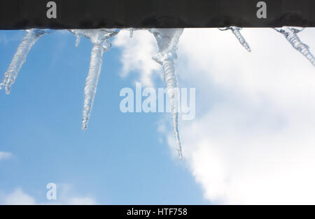 Ghiaccioli sospesi dal tetto del ghiaccio contro il cielo Foto Stock