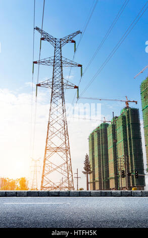 La trasmissione di energia elettrica pilone stagliano contro il cielo blu al tramonto Foto Stock