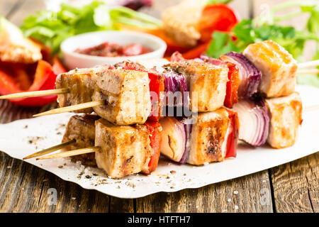 Grigliate gli spiedini di pollo con verdure sul tavolo di legno Foto Stock