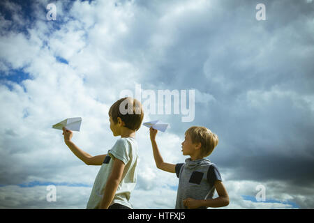 Ragazzi piccoli con piani di carta contro il cielo blu. Basso angolo di visione Foto Stock