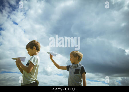 Ragazzi piccoli con piani di carta contro il cielo blu. Basso angolo di visione Foto Stock