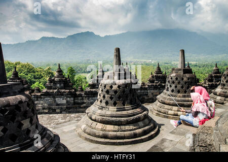 Giavanesi studentesse prendendo un selfie sulla sommità del tempio di Borobudur in Java centrale, Indonesia Foto Stock