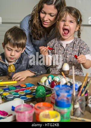 Foto di una madre e i suoi figli la pittura e decorazione di uova sode per la Pasqua. Foto Stock